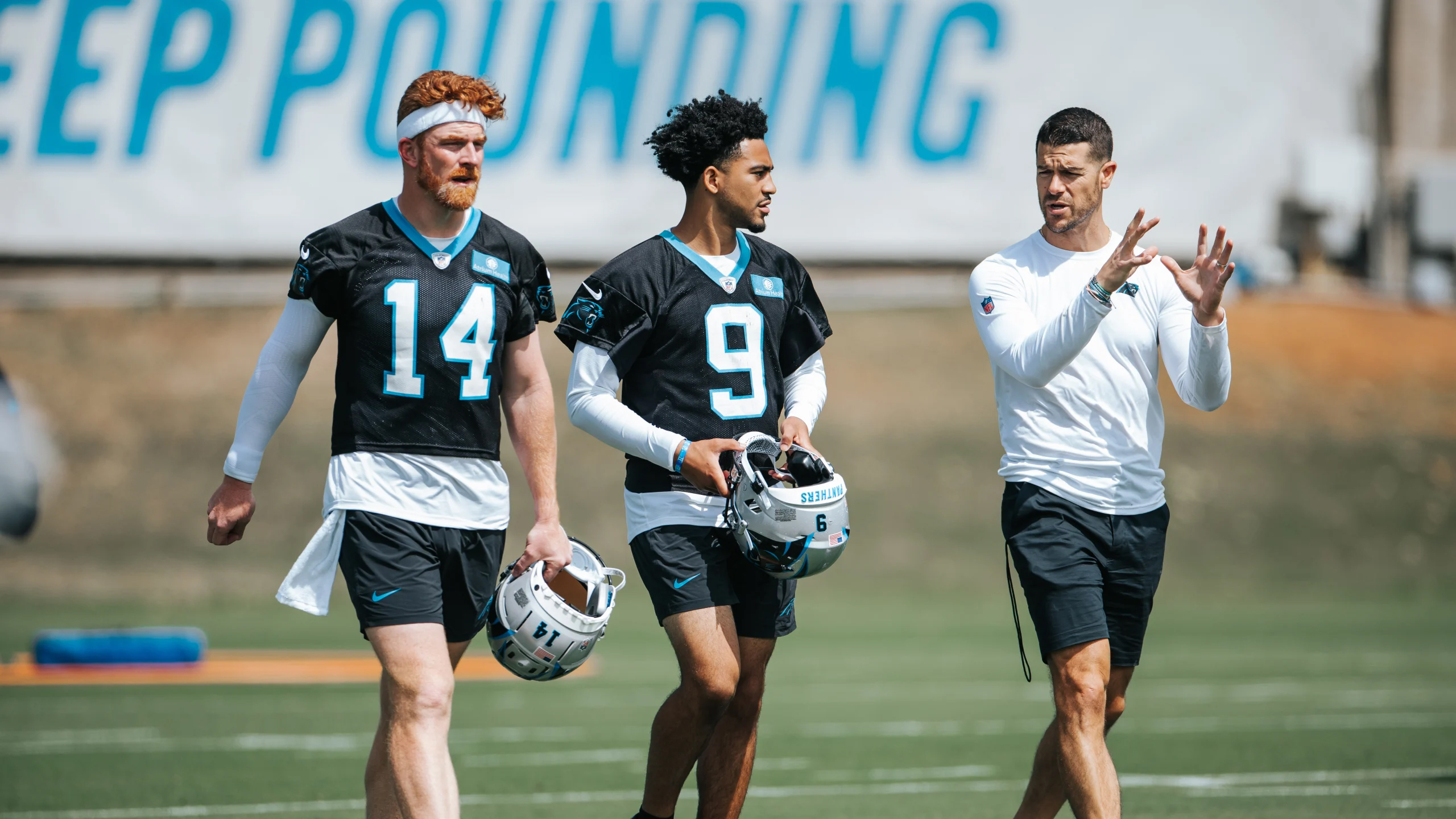 Carolina Panthers quarterbacks Andy Dalton and Bryce Young talk with head coach Dave Canales during voluntary minicamp April 24 at Bank of America Stadium.